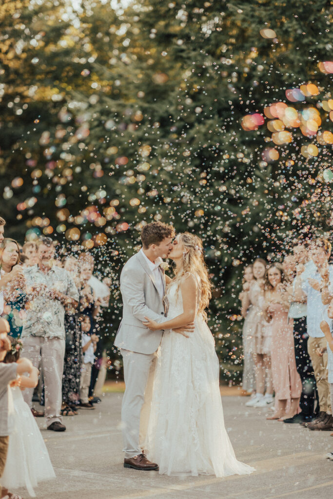 bride and groom kiss in bubble wedding exit