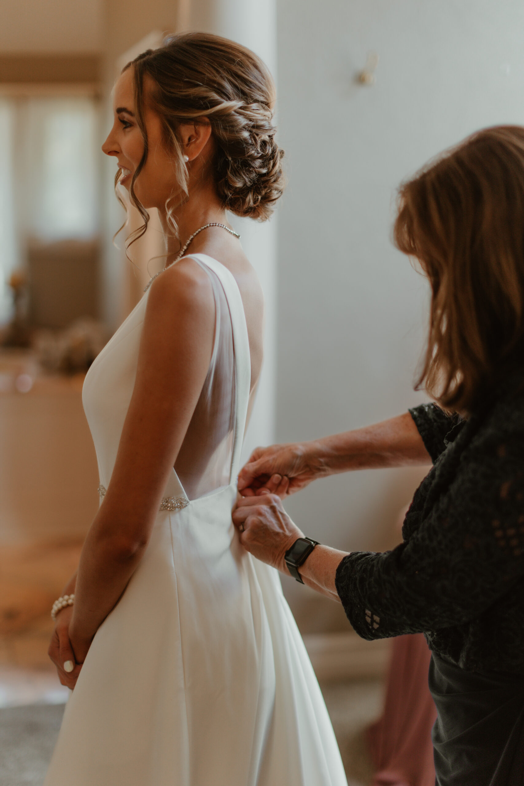 mother zipping up brides dress