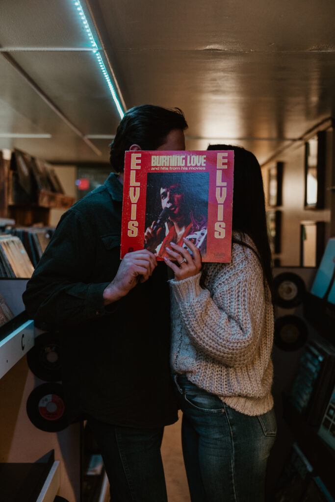 couple kissing behind a record at the record store