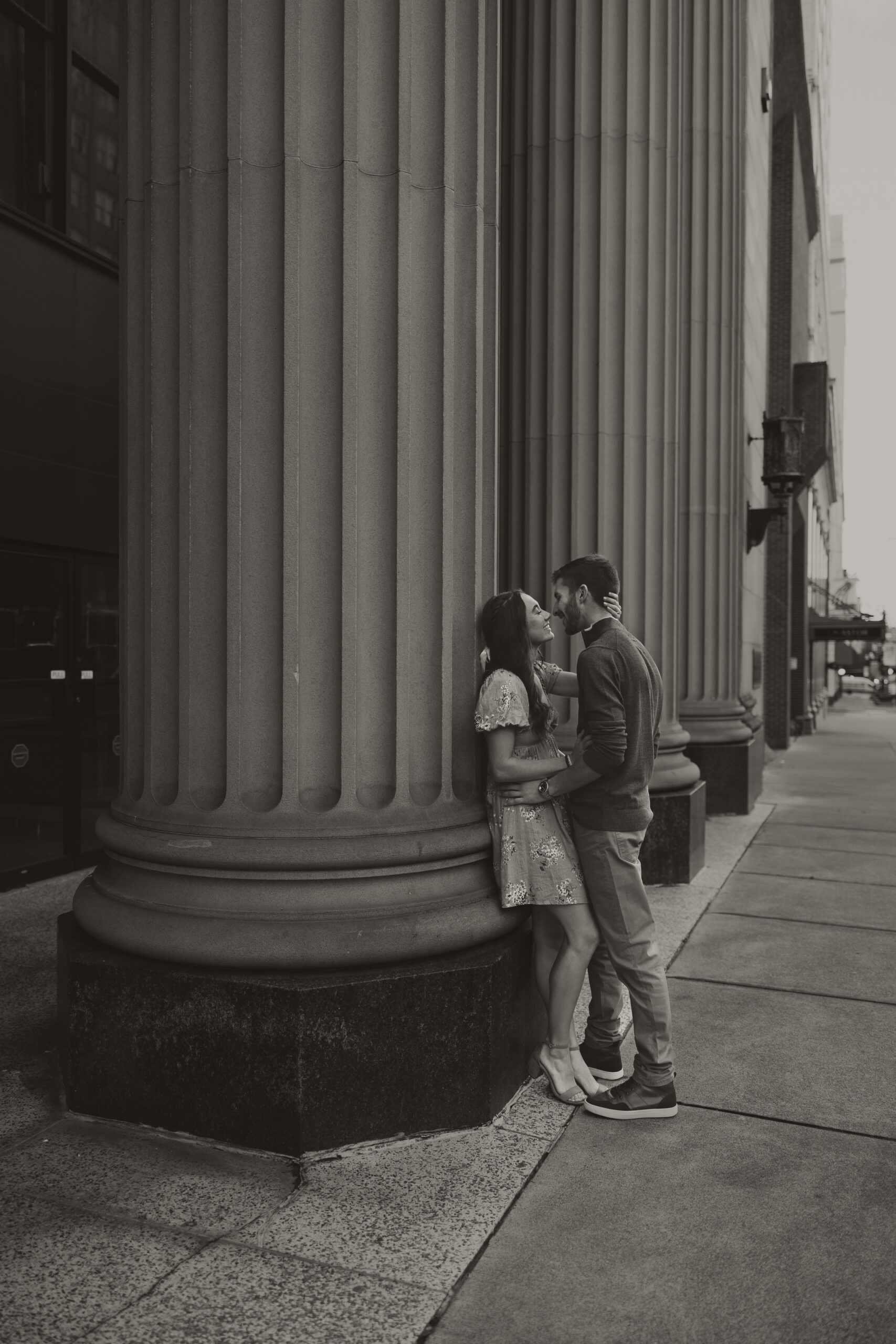 man and woman kissing against a post