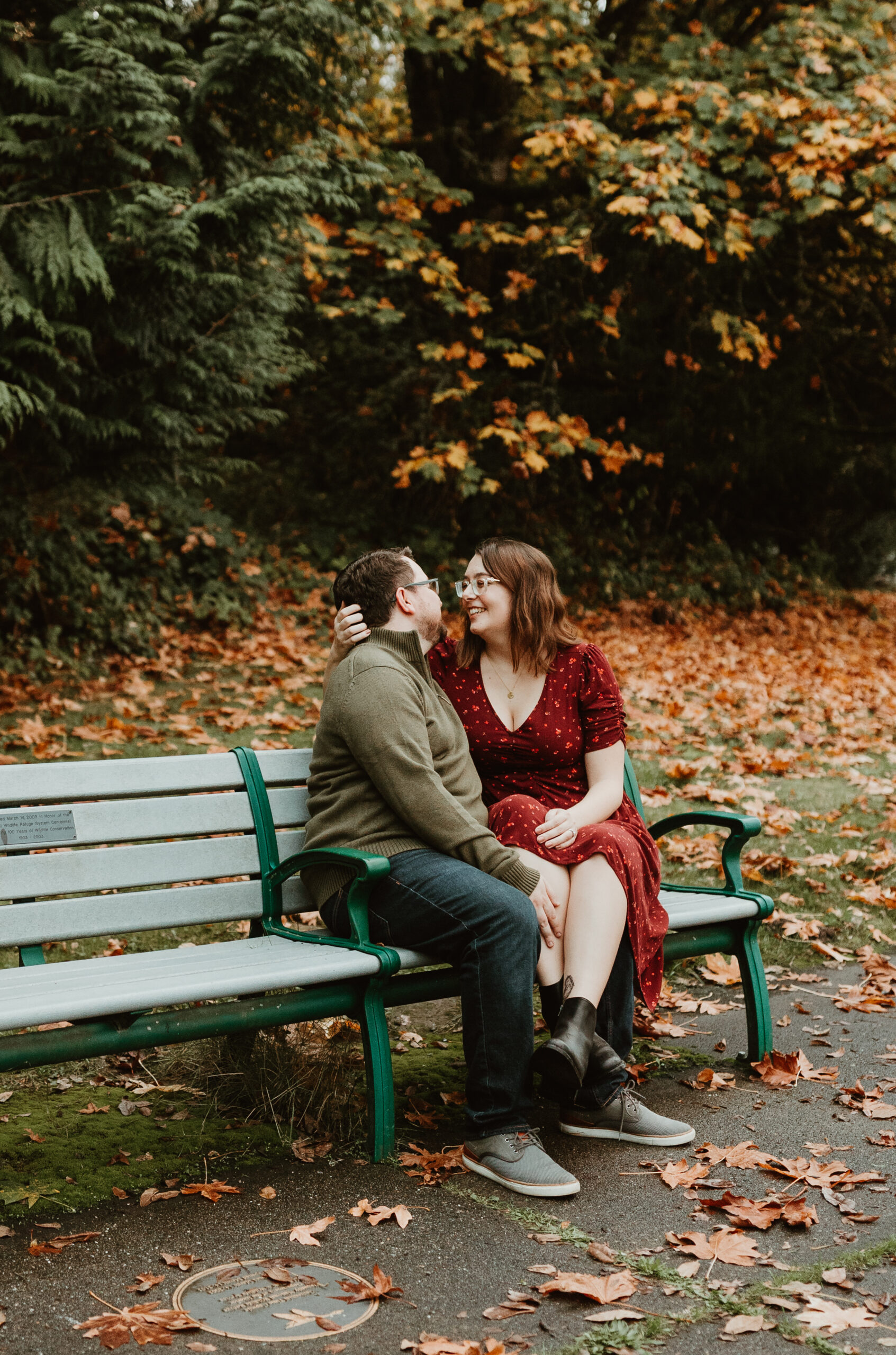 man and his fiancé sitting on a bench and looking at each other 