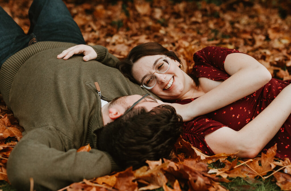 man and woman laying on the ground with her head resting on him