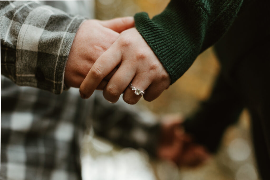 man and woman holding hands showing her engagement ring