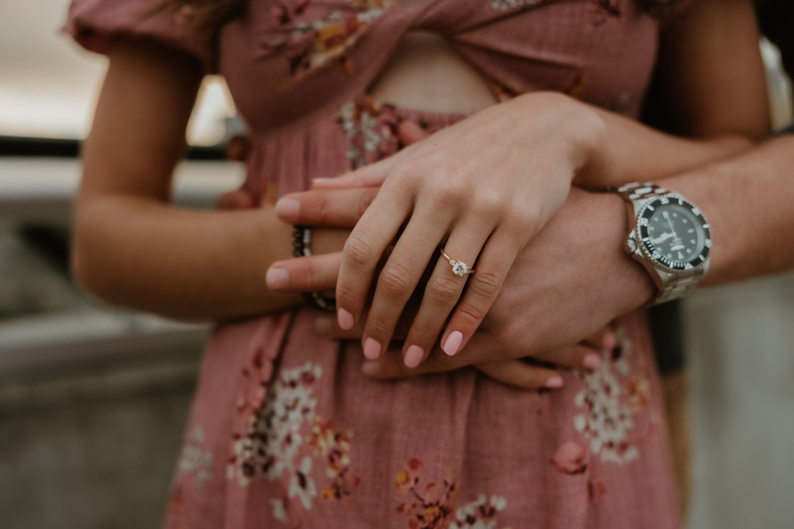 couple holding hands and showing her ring in their engagement session