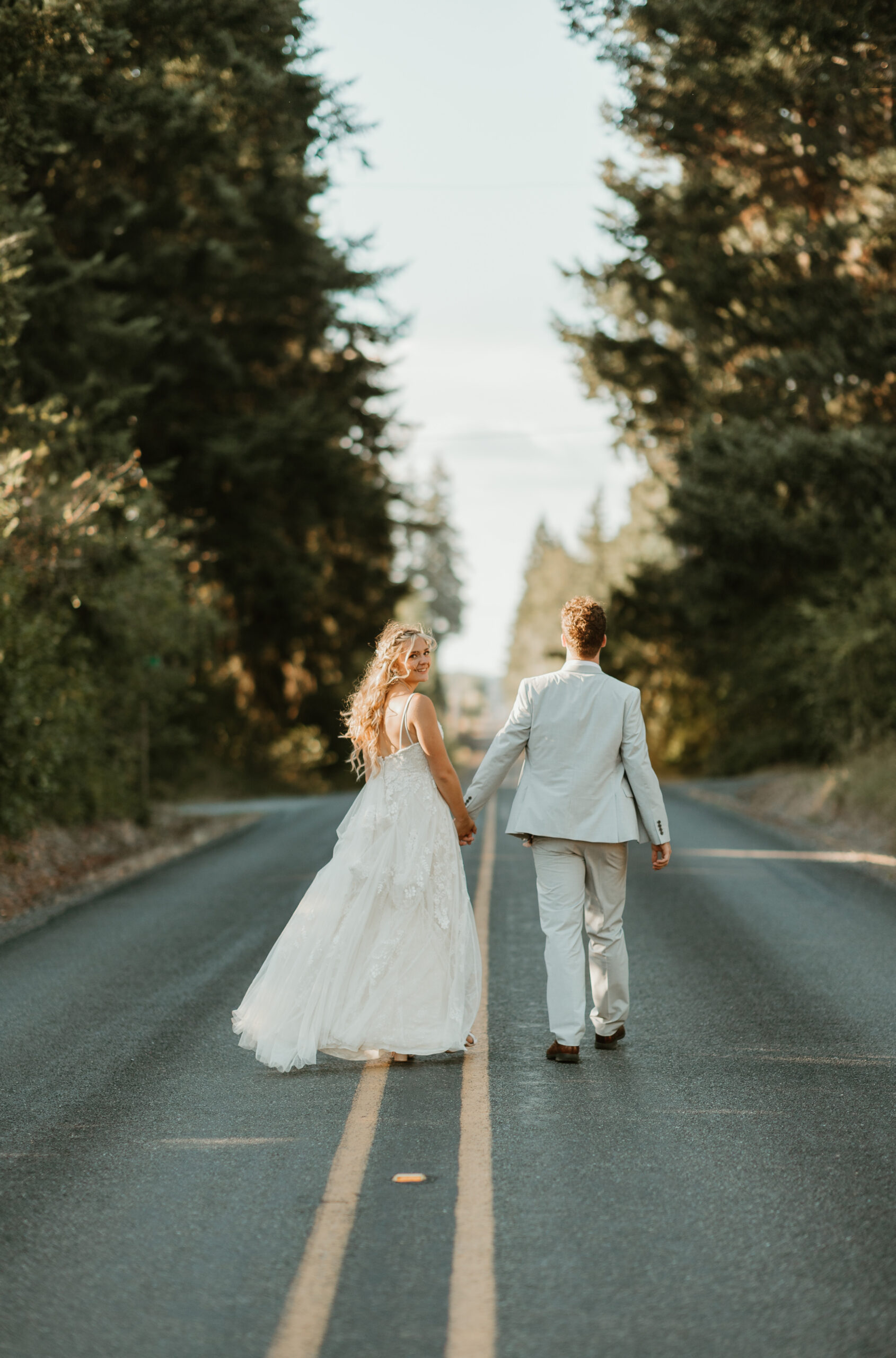 bride running on the road and holding hands with her groom