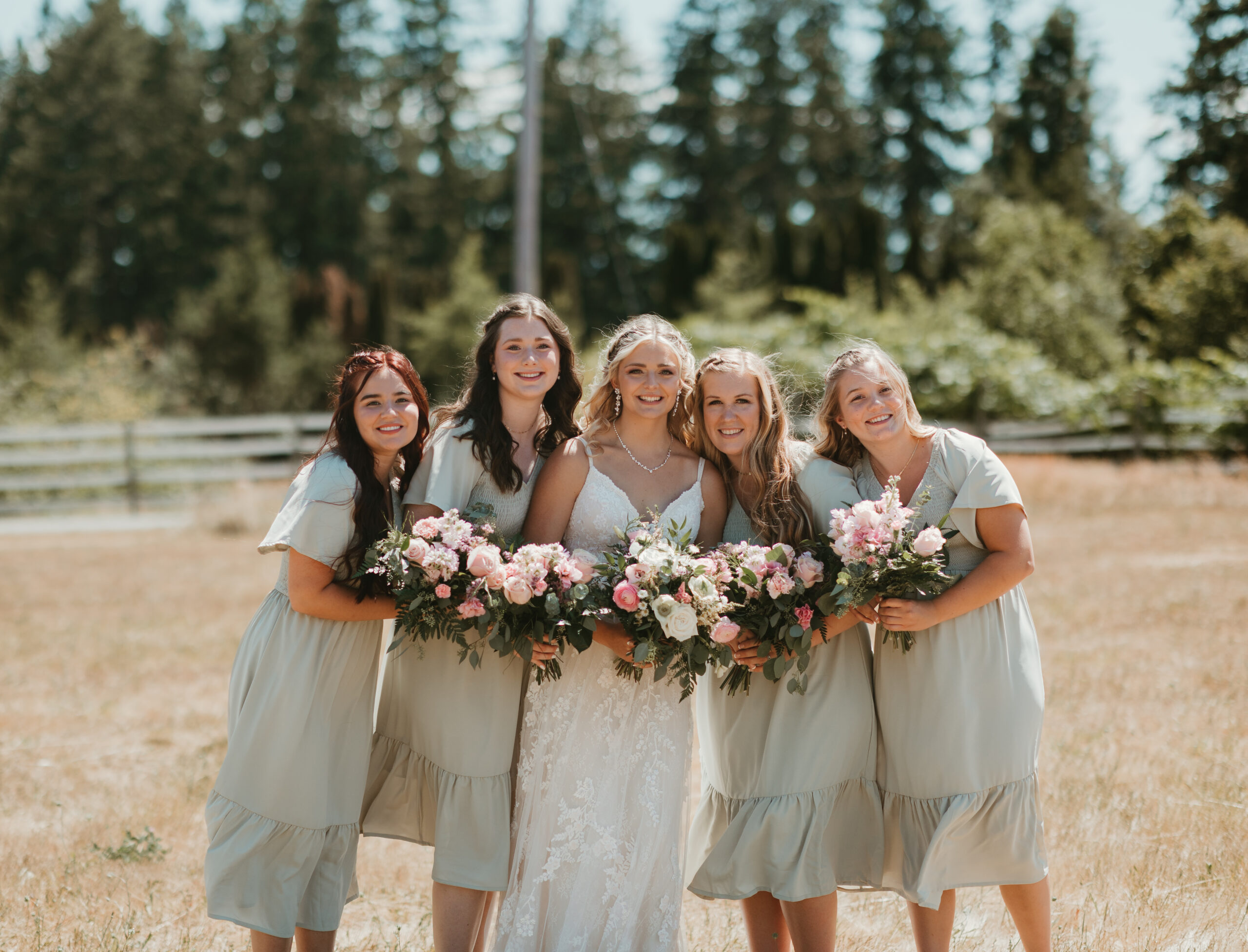 bride and her bridesmaids smiling in a field