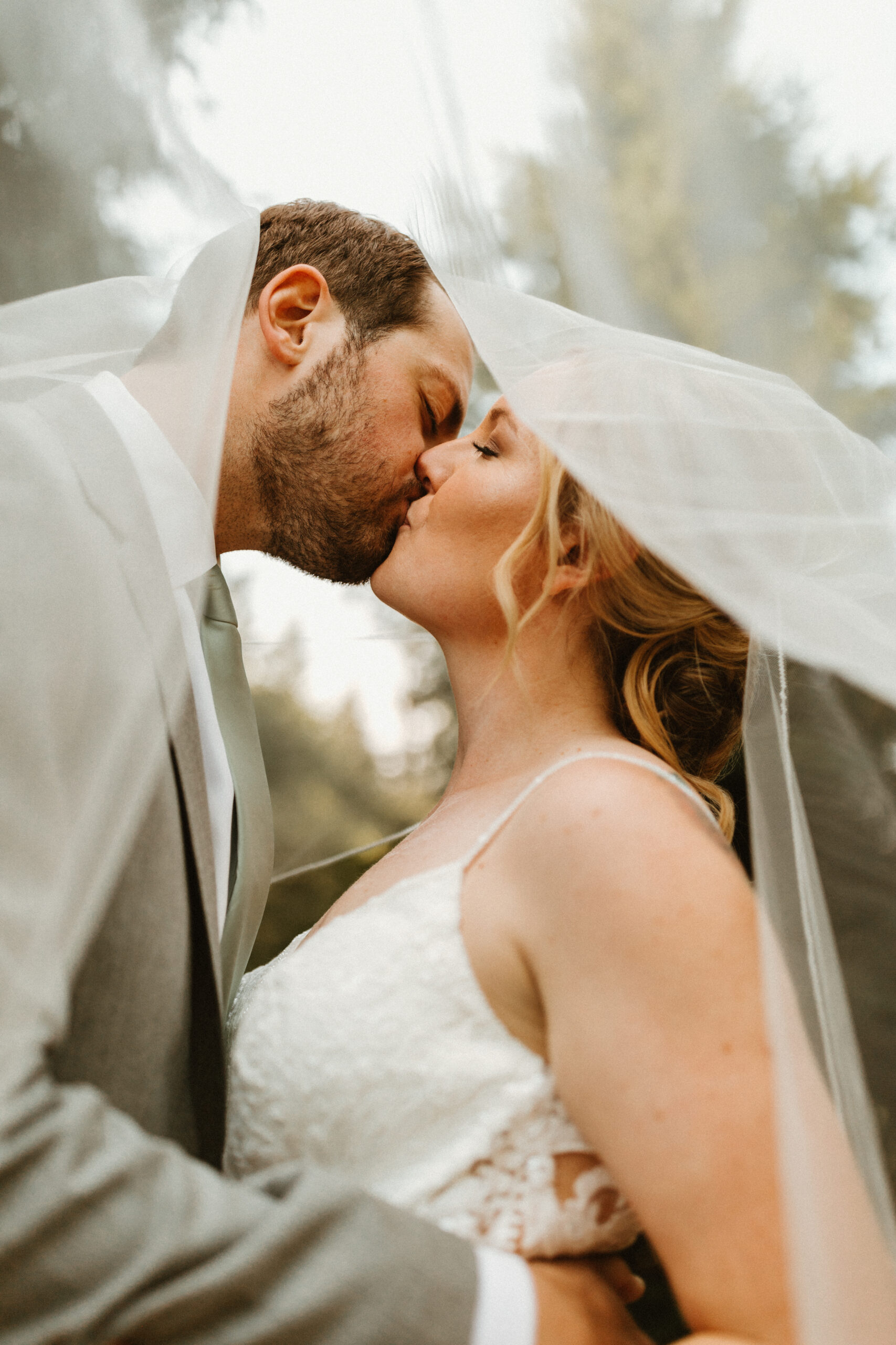 bride and groom kissing under he veil 