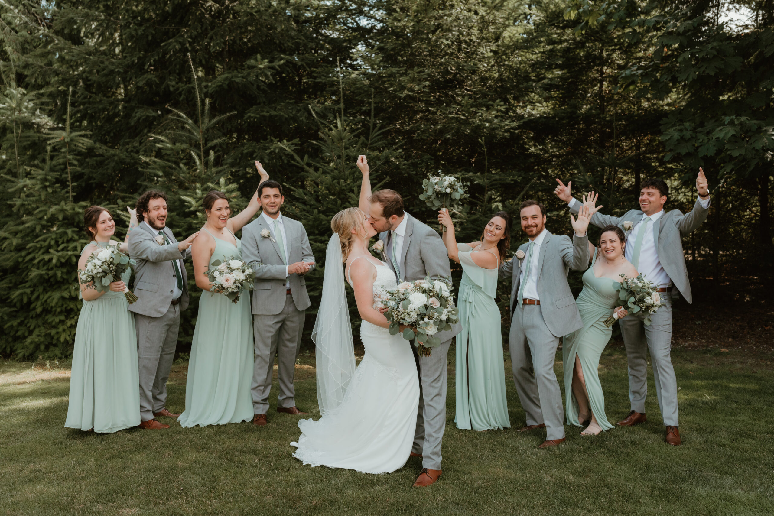 bride and groom kissing with their bridal party celebrating around them