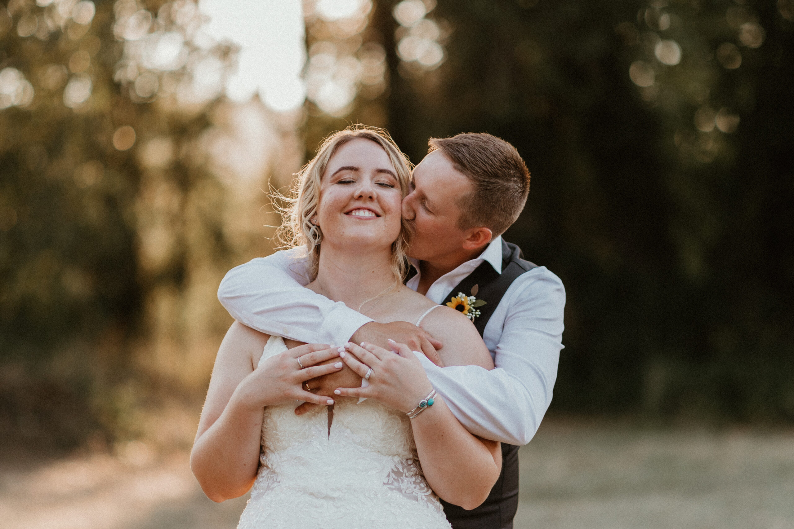 groom kissing his bride in a field 