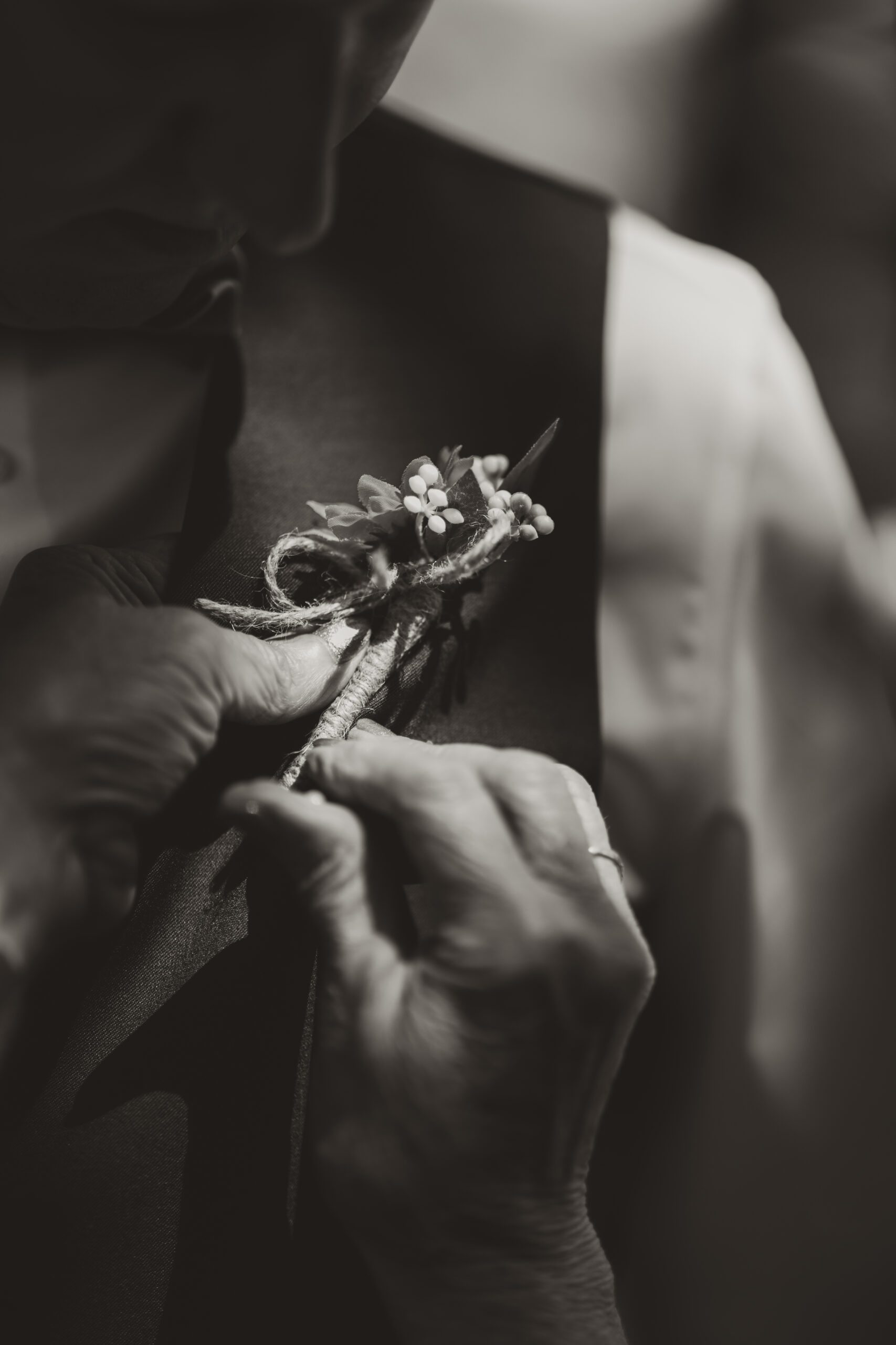 mother of the groom placing a boutonniere on her son 