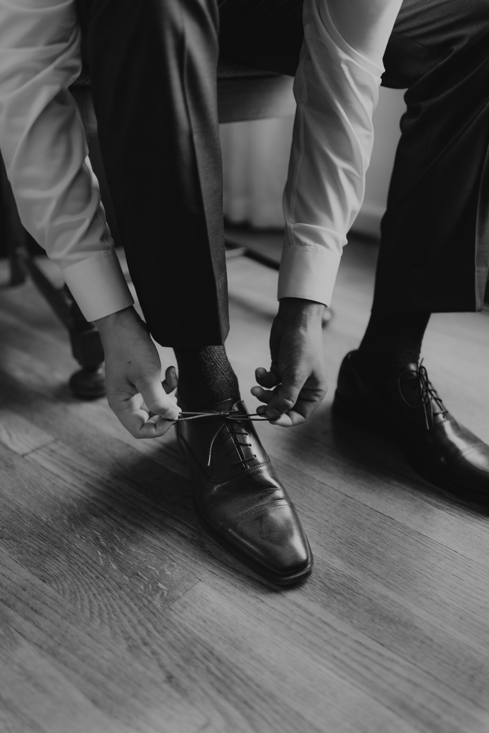 groom tying his shoe in a house